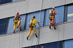 Industriekletterer reinigt eine moderne Glasfassade in großer Höhe und sorgt für professionelle Fassadenreinigung in Frankfurt.